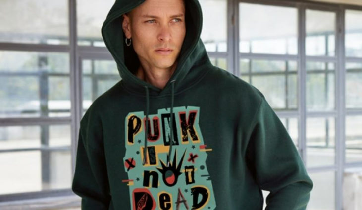 man wearing a forest green hoodie with a design that says "punk is not dead"